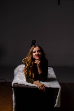 Güzel dansçı. Kız model. Kız bir şapkanın içinde oturuyor ve masaya oturuyor. Güzel iç çamaşırlı bir kız. Kız masada oturuyor ve maskaralık yapıyor, surat asıyor. pürüzsüz, bakımlı bacaklar.