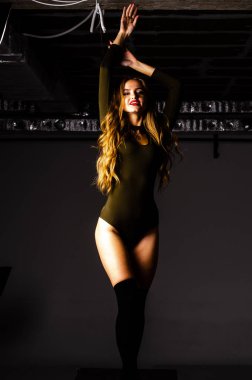 Güzel dansçı. Kız model. Kız bir şapkanın içinde oturuyor ve masaya oturuyor. Güzel iç çamaşırlı bir kız. Kız masada oturuyor ve maskaralık yapıyor, surat asıyor. pürüzsüz, bakımlı bacaklar.