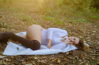 Ormanda poz veren beyaz elbiseli seksi bir genç kız.