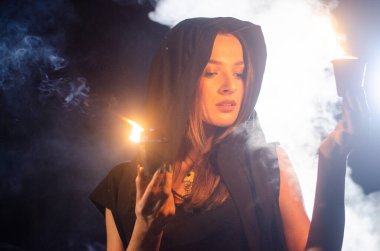 Gizemli genç kız siyah pelerin giyiyor, cadıların Şenlik ateşinin yanındaki ormanda Şabat günü