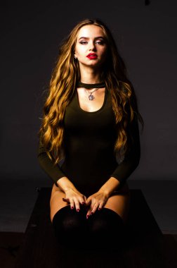 Güzel dansçı. Kız model. Kız bir şapkanın içinde oturuyor ve masaya oturuyor. Güzel iç çamaşırlı bir kız. Kız masada oturuyor ve maskaralık yapıyor, surat asıyor. pürüzsüz, bakımlı bacaklar.
