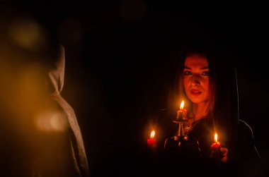 Siyah pelerin giyen gizemli genç kız, Şenlik ateşinin olduğu gece ormanda cadı ayini.