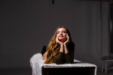 Güzel dansçı. Kız model. Kız bir şapkanın içinde oturuyor ve masaya oturuyor. Güzel iç çamaşırlı bir kız. Kız masada oturuyor ve maskaralık yapıyor, surat asıyor. pürüzsüz, bakımlı bacaklar.