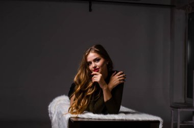 Güzel dansçı. Kız model. Kız bir şapkanın içinde oturuyor ve masaya oturuyor. Güzel iç çamaşırlı bir kız. Kız masada oturuyor ve maskaralık yapıyor, surat asıyor. pürüzsüz, bakımlı bacaklar.