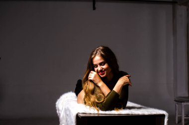 Güzel dansçı. Kız model. Kız bir şapkanın içinde oturuyor ve masaya oturuyor. Güzel iç çamaşırlı bir kız. Kız masada oturuyor ve maskaralık yapıyor, surat asıyor. pürüzsüz, bakımlı bacaklar.