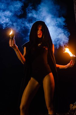 Siyah pelerin giyen gizemli genç kız, Şenlik ateşinin olduğu gece ormanda cadı ayini.