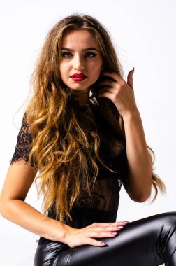 deri kıyafet giyen siyah saçlı kız tam uzunlukta portre. bir silah tutarken oturmuş poz, beyaz bir stüdyo arka plan üzerinde izole.