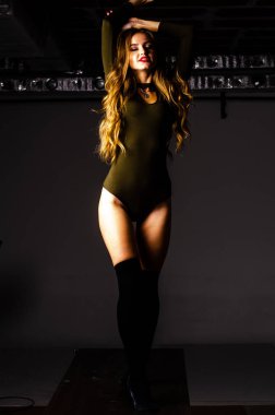 Güzel dansçı. Kız model. Kız bir şapkanın içinde oturuyor ve masaya oturuyor. Güzel iç çamaşırlı bir kız. Kız masada oturuyor ve maskaralık yapıyor, surat asıyor. pürüzsüz, bakımlı bacaklar.