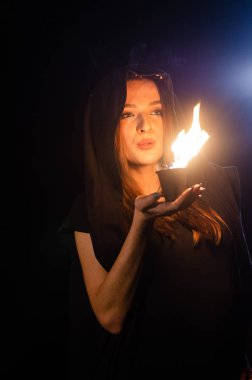 Siyah pelerin giyen gizemli genç kız, Şenlik ateşinin olduğu gece ormanda cadı ayini.