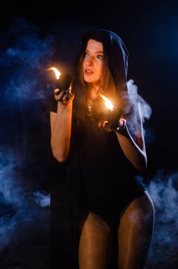 Gizemli genç kız siyah pelerin giyiyor, cadıların Şenlik ateşinin yanındaki ormanda Şabat günü