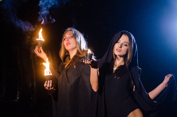 таинственные девушки в черных плащах, шабаш ведьм в лесу ночью у костра