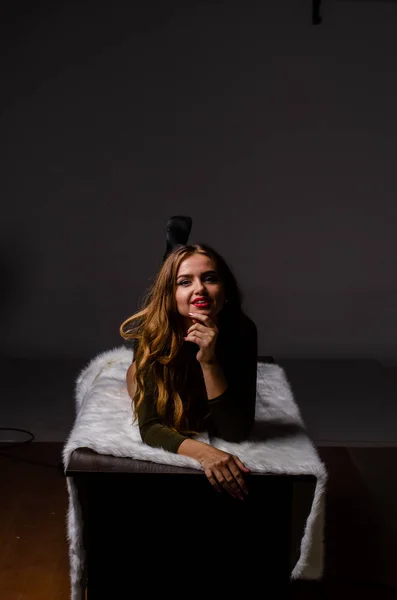 Bela dançarina. Modelo de rapariga. a menina senta-se em um chapéu e senta-se em uma mesa. menina em uma bela roupa interior. a menina está sentada na mesa e brincando, fazendo caras. pernas lisas e bem tratadas — Fotografia de Stock