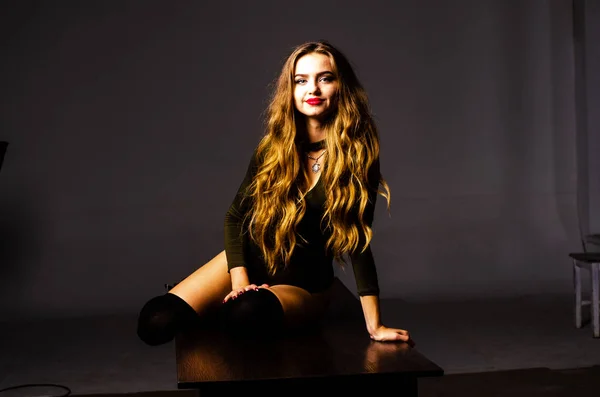 Beautiful dancer. Girl model. the girl sits in a hat and sits on a table. girl in a beautiful underwear. the girl is sitting on the table and fooling around, making faces. smooth, well-groomed legs — Stock Photo, Image