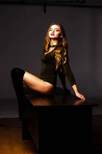 Beautiful dancer. Girl model. the girl sits in a hat and sits on a table. girl in a beautiful underwear. the girl is sitting on the table and fooling around, making faces. smooth, well-groomed legs — 스톡 사진