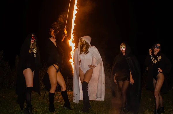 黒と白の服を着た謎の少女たちたき火で夜の森の中の魔女の安息日 — ストック写真