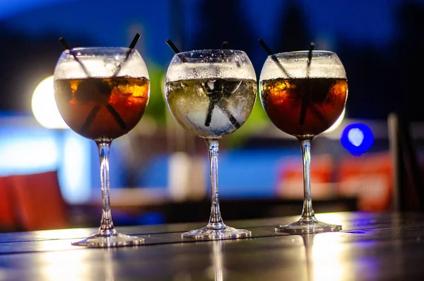 Beautiful row line of different colored alcohol cocktails on a party, martini, vodka,and others on decorated catering bouquet table on open air event, picture with beautiful bokeh — Stock Photo, Image