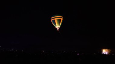 Sıcak hava balonu gökyüzü altında Samanyolu ve geceleri parlayan yıldızla muhteşem bir kapadokya uçuyor.  