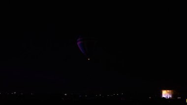 Sıcak hava balonu gökyüzü altında Samanyolu ve geceleri parlayan yıldızla muhteşem bir kapadokya uçuyor.  