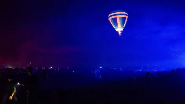 Warme lucht ballon vliegen over spectaculaire Cappadocië onder de hemel met melkachtige manier en glanzende ster 's nachts (met graan) — Stockfoto