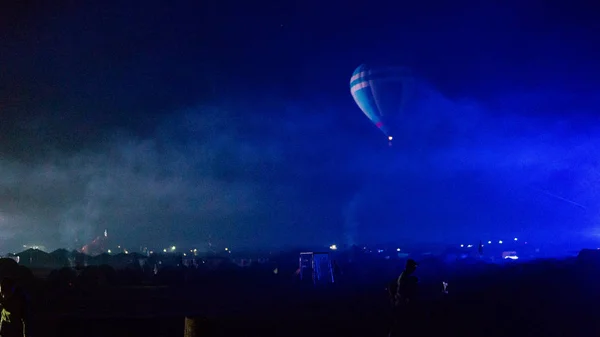 Воздушный шар, летящий над захватывающей Каппадокией под небом с молочной дорогой и сияющей звездой ночью (с зерном ) — стоковое фото