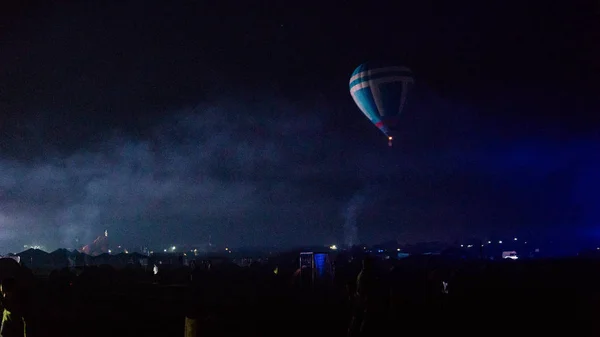 Воздушный шар, летящий над захватывающей Каппадокией под небом с молочной дорогой и сияющей звездой ночью (с зерном ) — стоковое фото