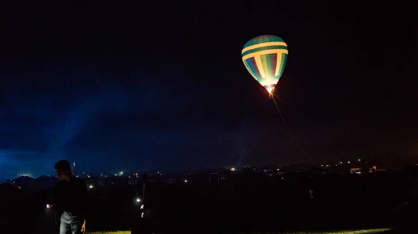 Varmluftsballong flyr over spektakulær Kappadokia under himmelen med melkeaktig måte og skinnende stjerne om natten (med korn) ) – stockfoto