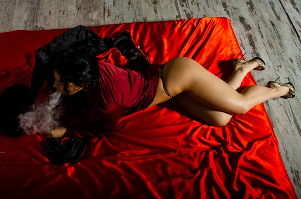 Сексуальная молодая женщина в черном нижнем белье, испаряющаяся в спальне. Красивая брюнетка курит — стоковое фото