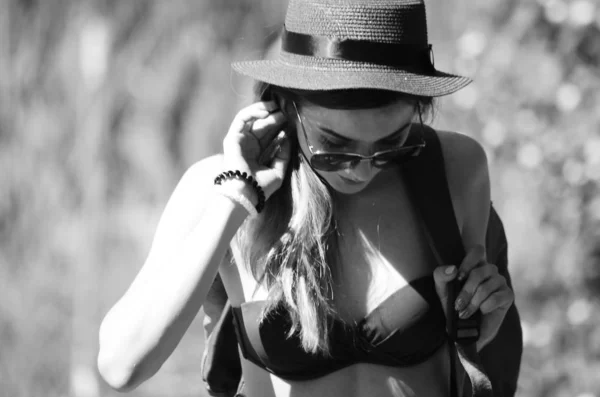 Meisje in een hoed en bril in een zwembroek op het strand poseren — Stockfoto
