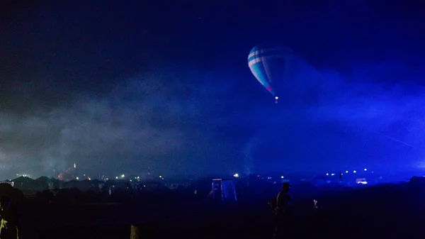 Balon na gorące powietrze przelatujący nad spektakularną Kapadocją pod niebem z Drogą Mleczną i świecącą gwiazdą w nocy (z ziarnem) — Zdjęcie stockowe