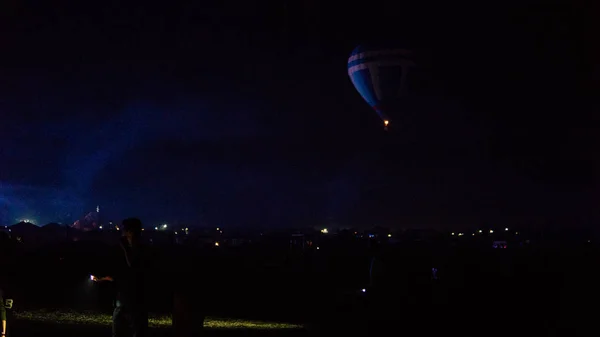 Воздушный шар, летящий над захватывающей Каппадокией под небом с молочной дорогой и сияющей звездой ночью (с зерном ) — стоковое фото