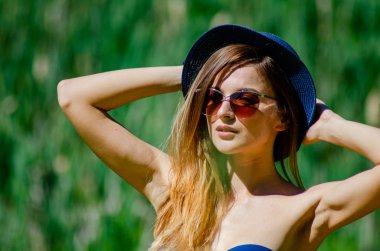 Kız şapka ve gözlük sahilde poz bir mayo