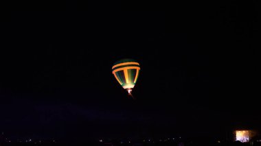 Sıcak hava balonu gökyüzü altında Samanyolu ve geceleri parlayan yıldızla muhteşem bir kapadokya uçuyor.  