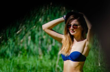 Kız şapka ve gözlük sahilde poz bir mayo