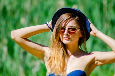 Kız şapka ve gözlük sahilde poz bir mayo