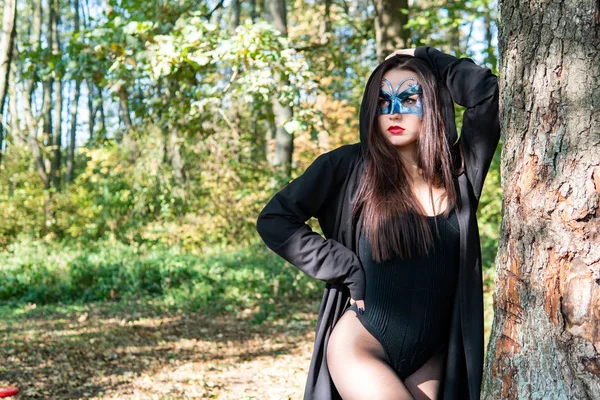 Bela Jovem Mulher Traje Carnaval Preto Máscara Posando Floresta — Fotografia de Stock