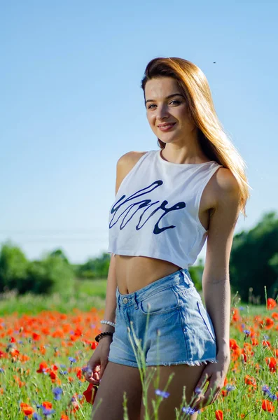 Wanita cantik di lapangan dari bunga poppy — Stok Foto