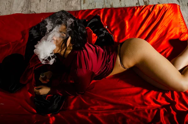Сексуальна молода жінка в чорній білизні парі в спальні. Красива брюнетка жінка курить — стокове фото