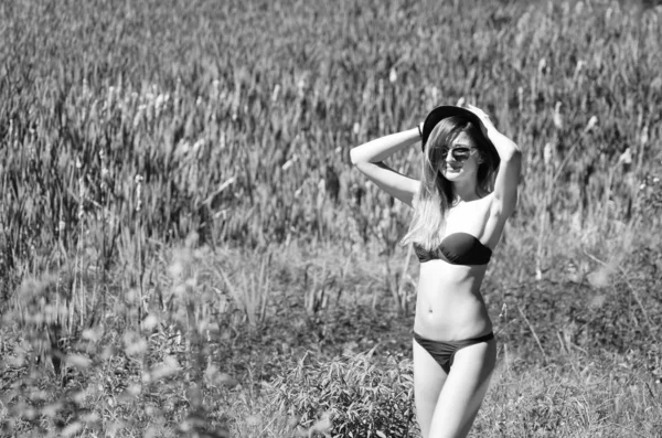 Chica con sombrero y gafas en traje de baño posando en la playa —  Fotos de Stock