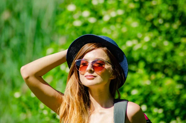 Girl in a hat and glasses in a swimsuit posing on the beach — Stock Photo, Image