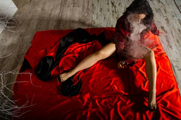 Σέξι νεαρή γυναίκα με μαύρα εσώρουχα που χοροπηδάει στην κρεβατοκάμαρα. Όμορφη μελαχρινή γυναίκα καπνίζει — Φωτογραφία Αρχείου