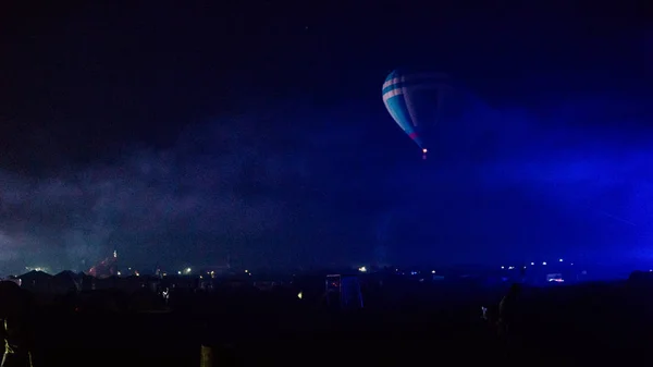 Warme lucht ballon vliegen over spectaculaire Cappadocië onder de hemel met melkachtige manier en glanzende ster 's nachts (met graan) — Stockfoto