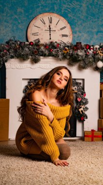 Noel süslemeli stüdyoda şöminenin yanında poz veren güzel esmer genç bir kadın. 