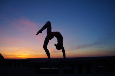Dans eden dansçı gün batımına karşı havada yarılır.