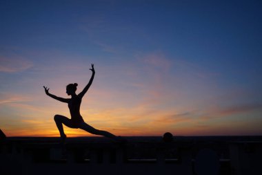 Dans eden dansçı gün batımına karşı havada yarılır.