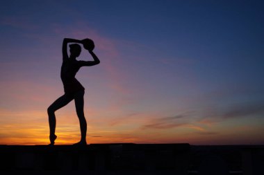Dans eden dansçı gün batımına karşı havada yarılır.