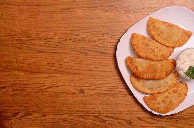 Özbek Doğu Tatar mutfağı, et ve suluguni ile cheburek peynirli sebze ve Yeşiller ahşap bir masa üzerinde beyaz bir tabak içinde.