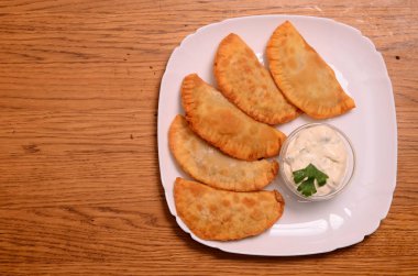 Özbek Doğu Tatar mutfağı, et ve suluguni ile cheburek peynirli sebze ve Yeşiller ahşap bir masa üzerinde beyaz bir tabak içinde.