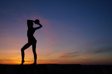 Dans eden dansçı gün batımına karşı havada yarılır.
