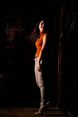 Güzel esmer model, karanlık odada poz veriyor. 