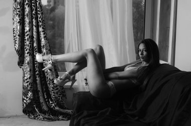 İç çamaşırlarıyla kanepede poz veren sevimli, çekici, çekici bir kızın portresi. 